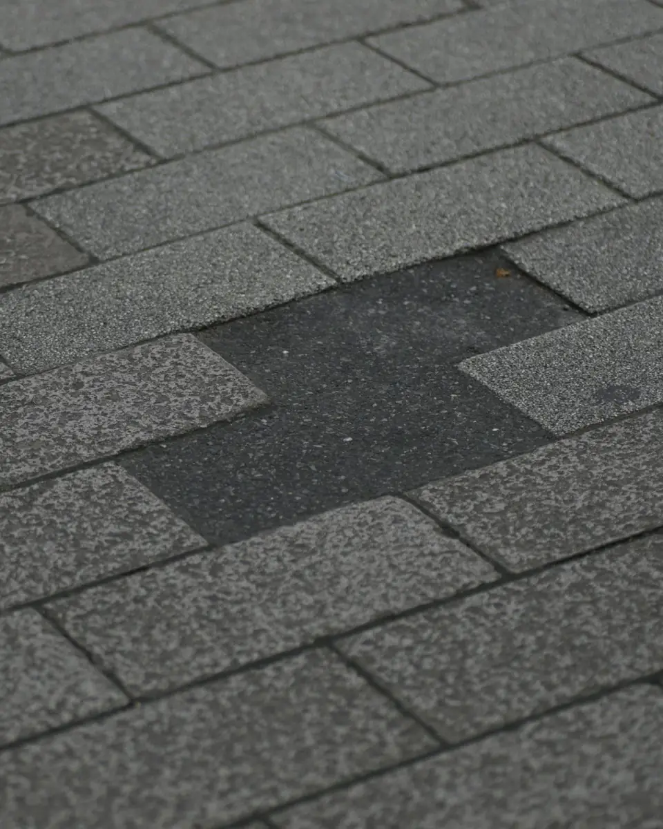 Close-up of storm-damaged asphalt shingles with missing tabs